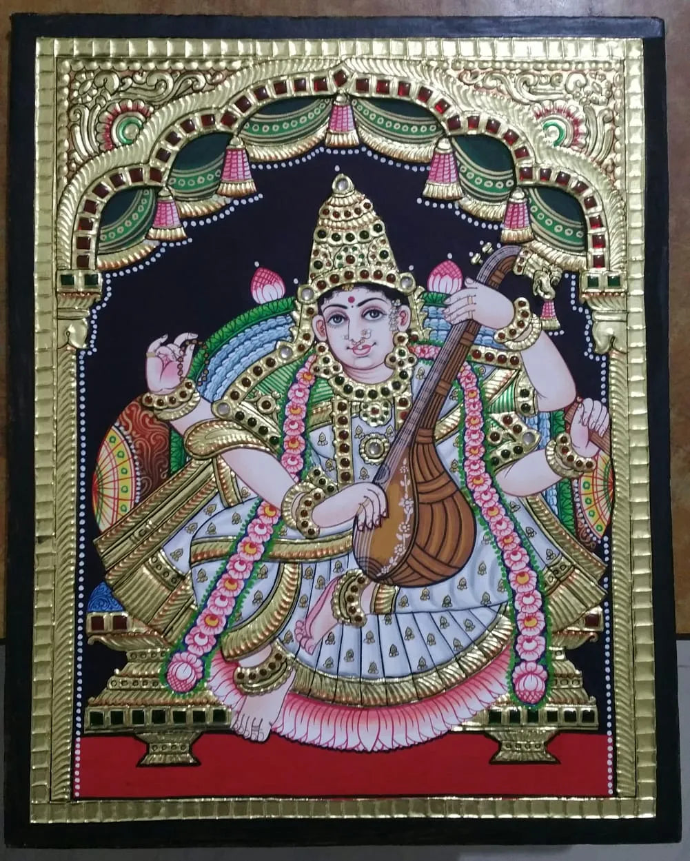 Decorative painting of a Goddess holding a musical instrument with intricate gold and color border Goddess_Saraswathiji tanjore painting 